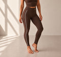 Legging Flowline chocolat – vue portée dynamique, logo blanc placé comme sur le modèle noir